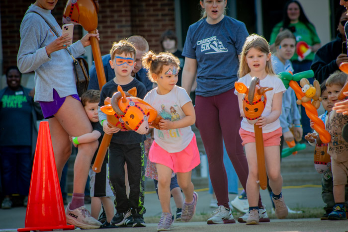 Children with face paint and blow-up horses run and play.