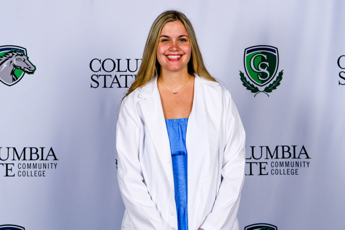A person poses in front if a white background.